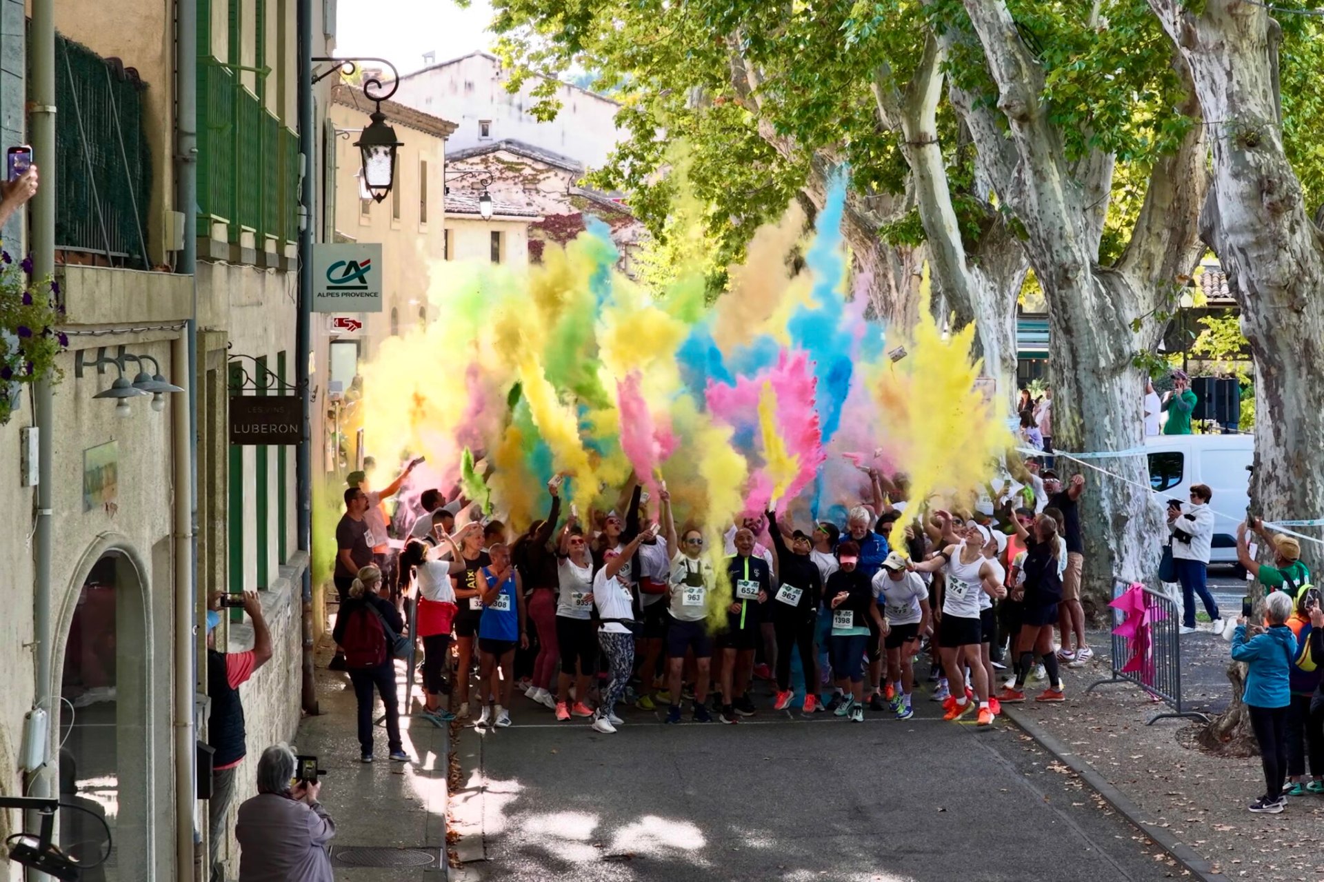 Coureurs joyeux sous des nuages de poudre colorée à Lourmarin